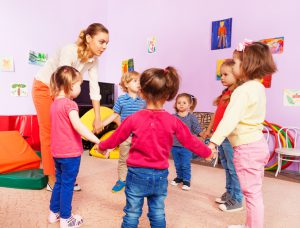 Teacher and group of kids in kindergarten roundelay in kindergarten lesson